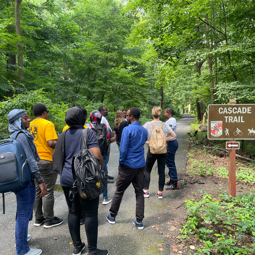 Participants at an environmental workshop at Patapsco Valley State Park gather near the sign for Cascade Trail preparing for a guided hike to the waterfall.
