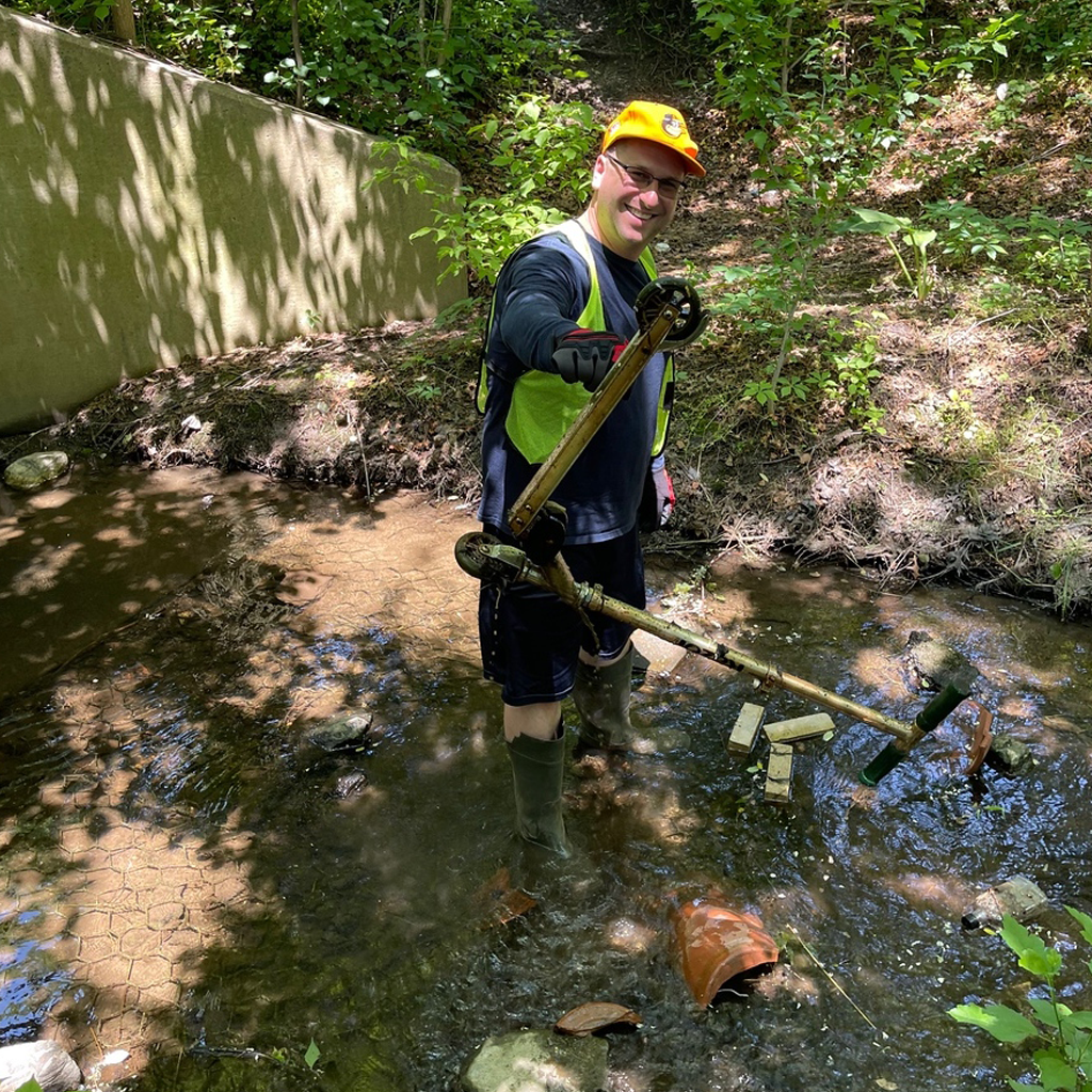 A volunteer holds up a scooter pulled from the stream at a Stream Cleanup stewardship event.
